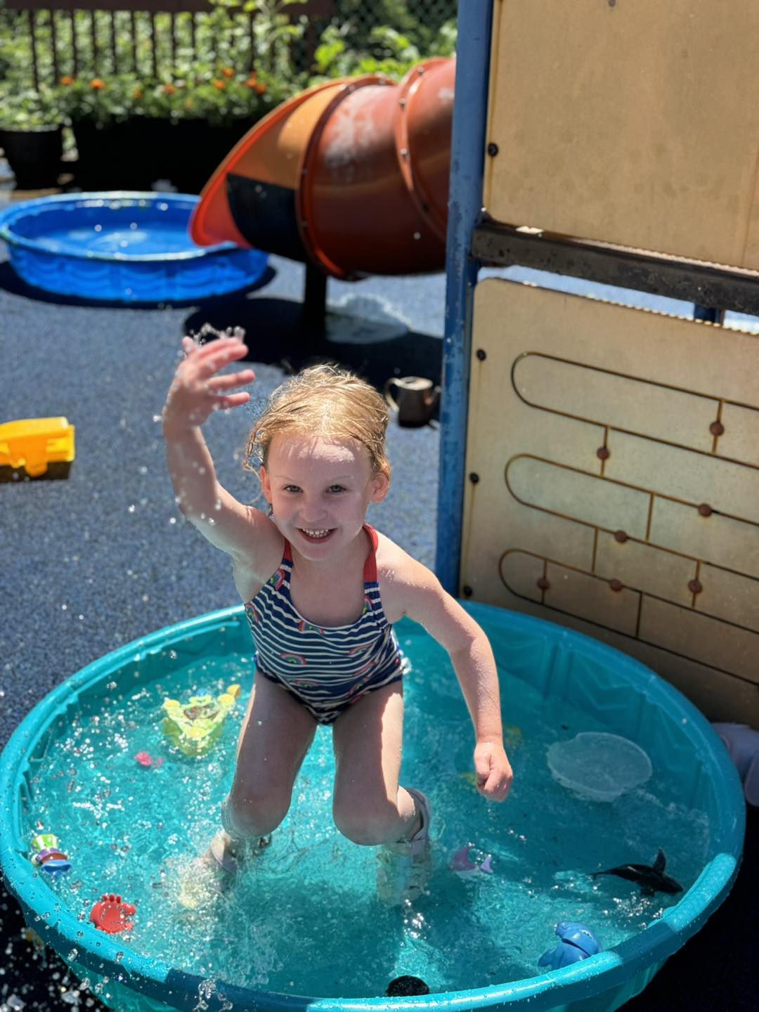 A child jumping happily into a small wading pool on the playground