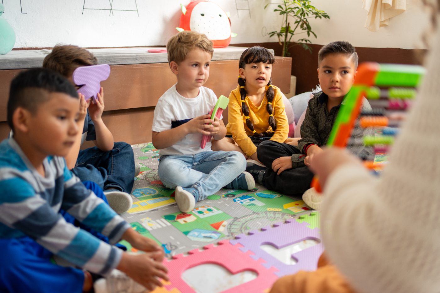 Preschoolers gathered on a play mat during a group lesson