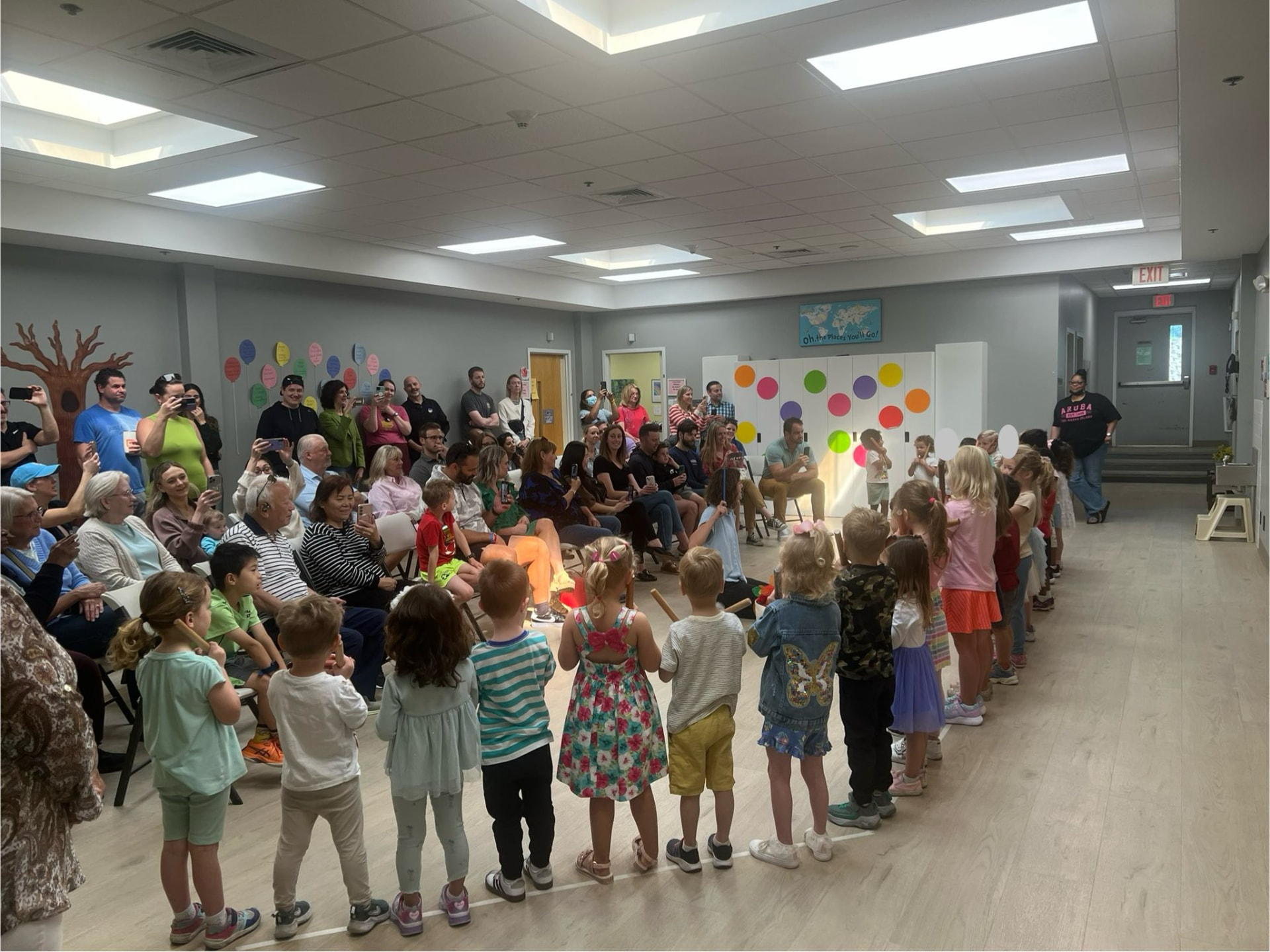 Children lined up performing for families in the community room