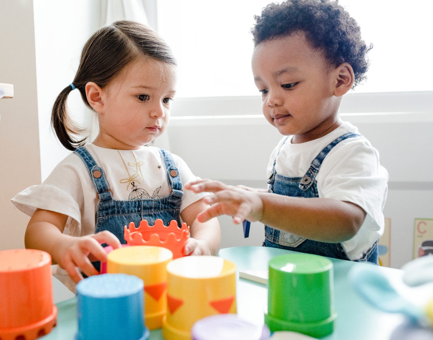 Two toddlers stacking colorful cups together