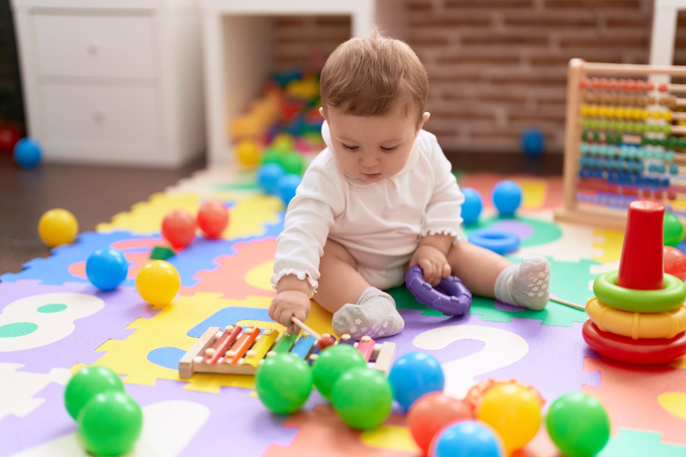 Baby exploring a xylophone on a colorful play mat